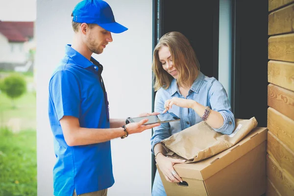 A woman is handing a package to a delivery man.