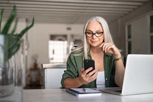 A woman sitting at a table looking at her phone.