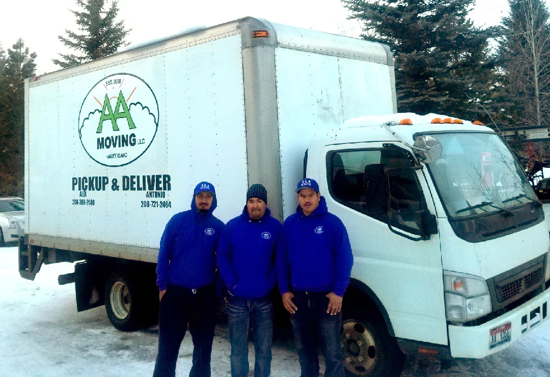 Three men standing in front of a moving truck.